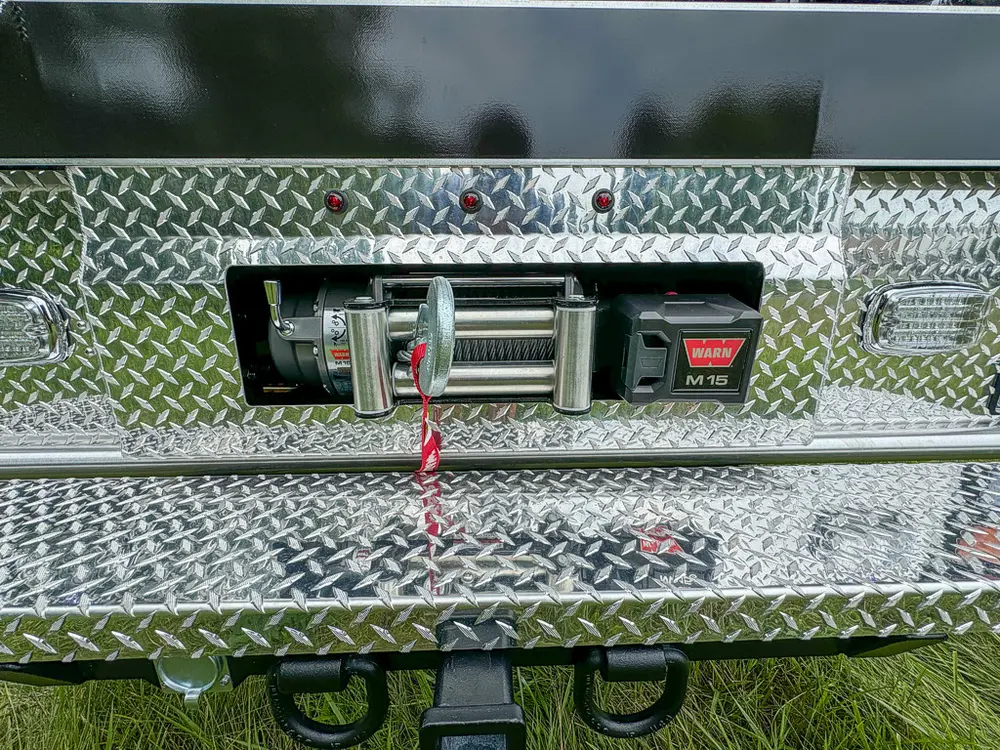 Rear bumper close-up with mounted winch in diamond-plate panel.