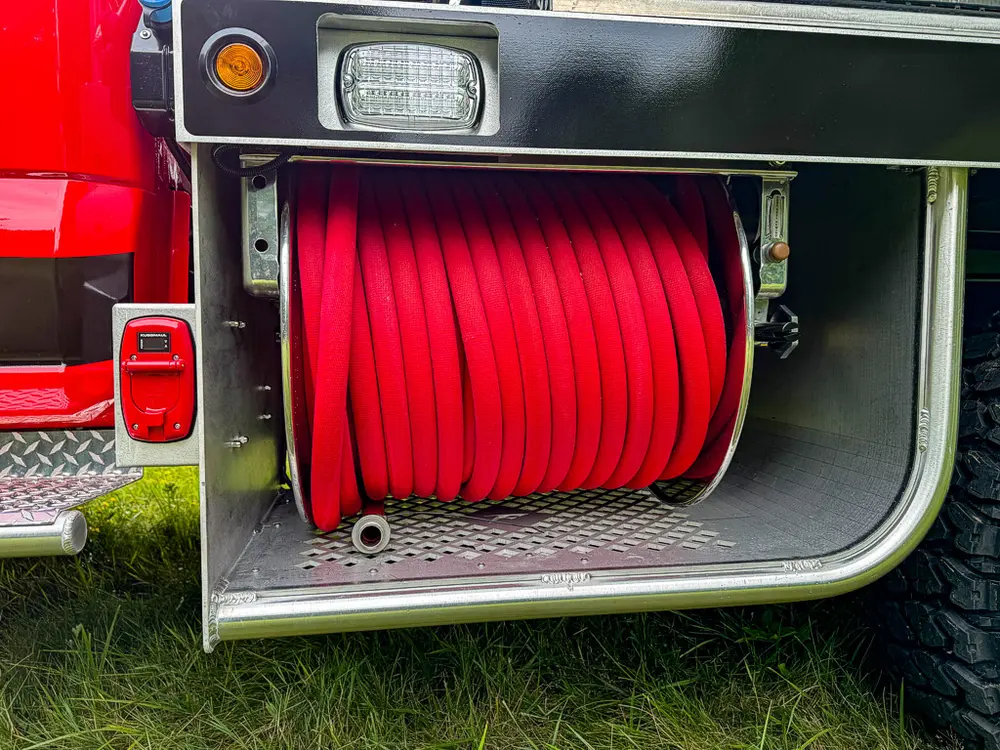 Lower side compartment close-up with red hose reel.