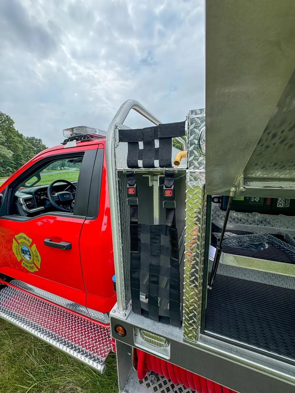 Vertical equipment rack behind cab with mounted red packs and straps.