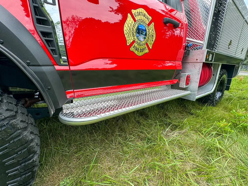 Side step and lower cab trim close-up beneath door emblem.