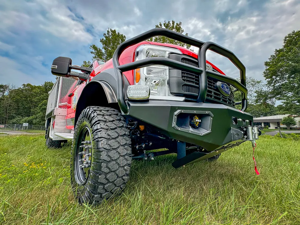 Low front-left corner view showing lifted stance and brush bumper.