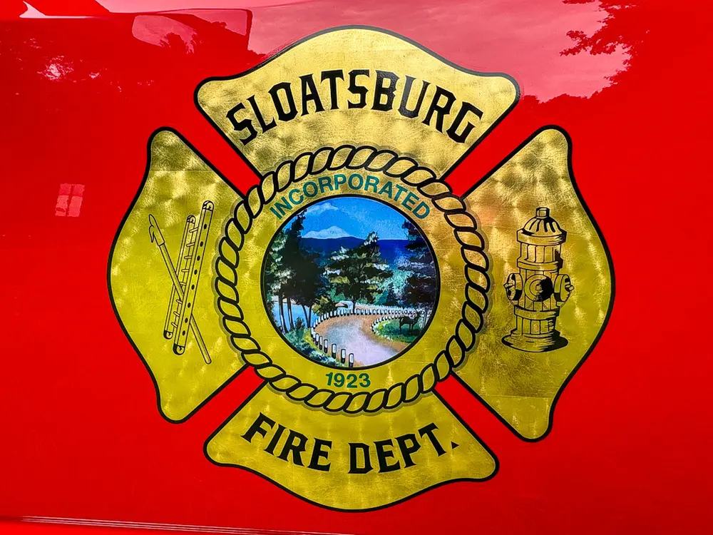 Close-up of Sloatsburg Fire Department crest on red door panel.
