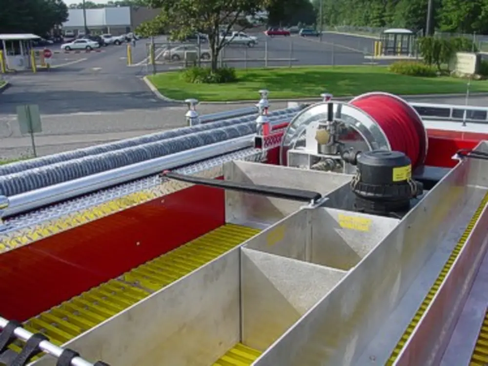 Exterior view of small fire truck showing cab, body compartments, and wheel/tire area.