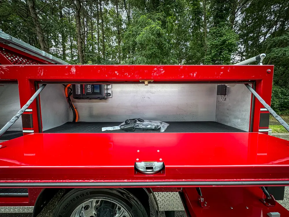 Long open top-side compartment with charger and stored items.