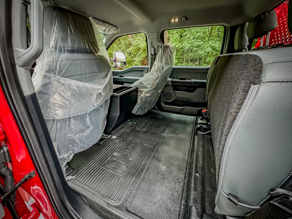 Rear floor and seatback area with open rear door and cab interior.