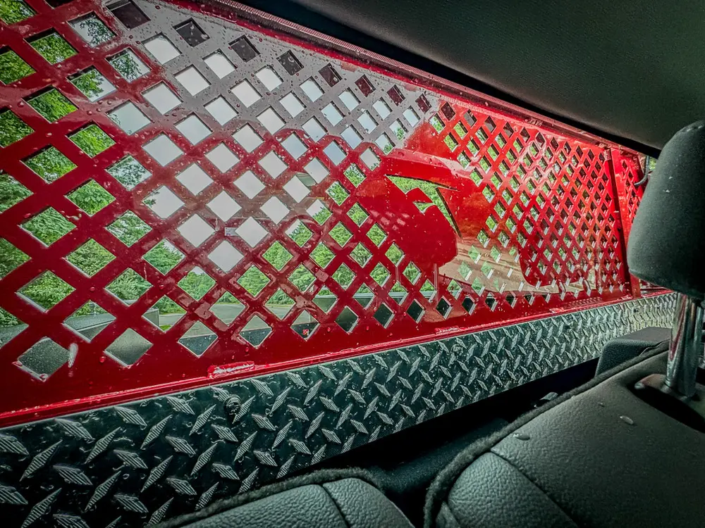 Interior rear divider close-up with red mesh and diamond-plate trim.