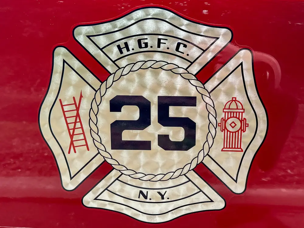 Close-up of fire department crest with number 25 on red body panel.