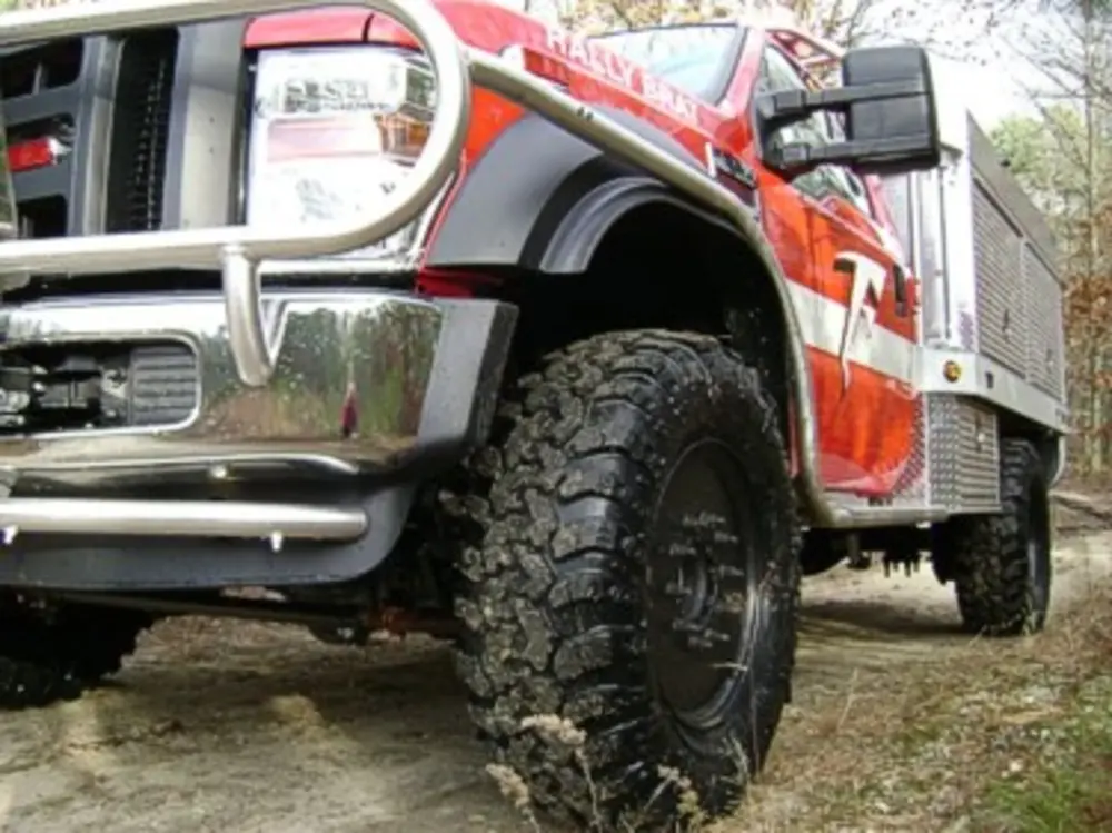 Exterior view of small fire truck showing cab, body compartments, and wheel/tire area.