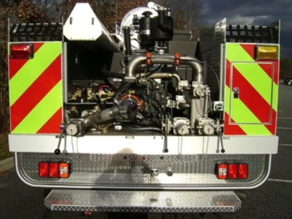 Exterior view of small fire truck showing cab, body compartments, and wheel/tire area.