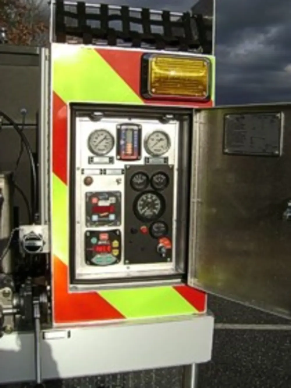 Exterior view of small fire truck showing cab, body compartments, and wheel/tire area.