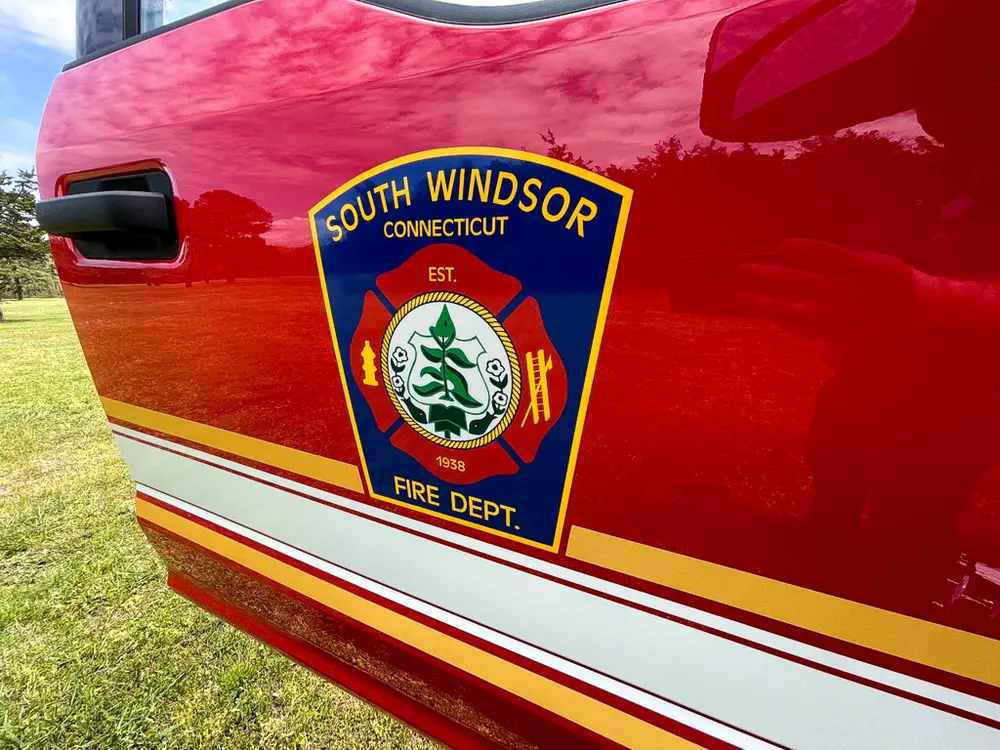 Exterior view of small fire truck showing cab, body compartments, and wheel/tire area.