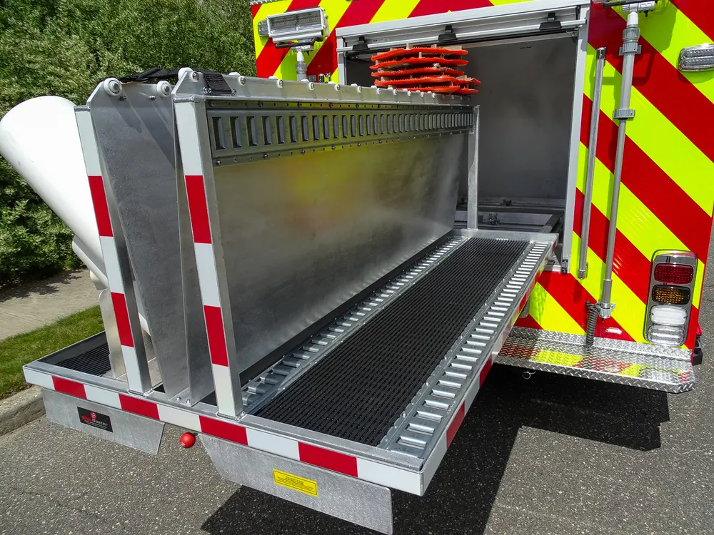 Exterior view of small fire truck showing cab, body compartments, and wheel/tire area.