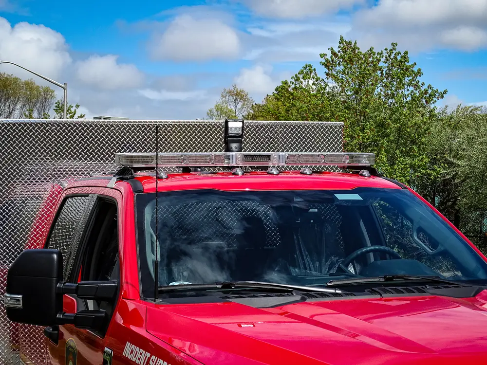 Exterior view of small fire truck showing cab, body compartments, and wheel/tire area.