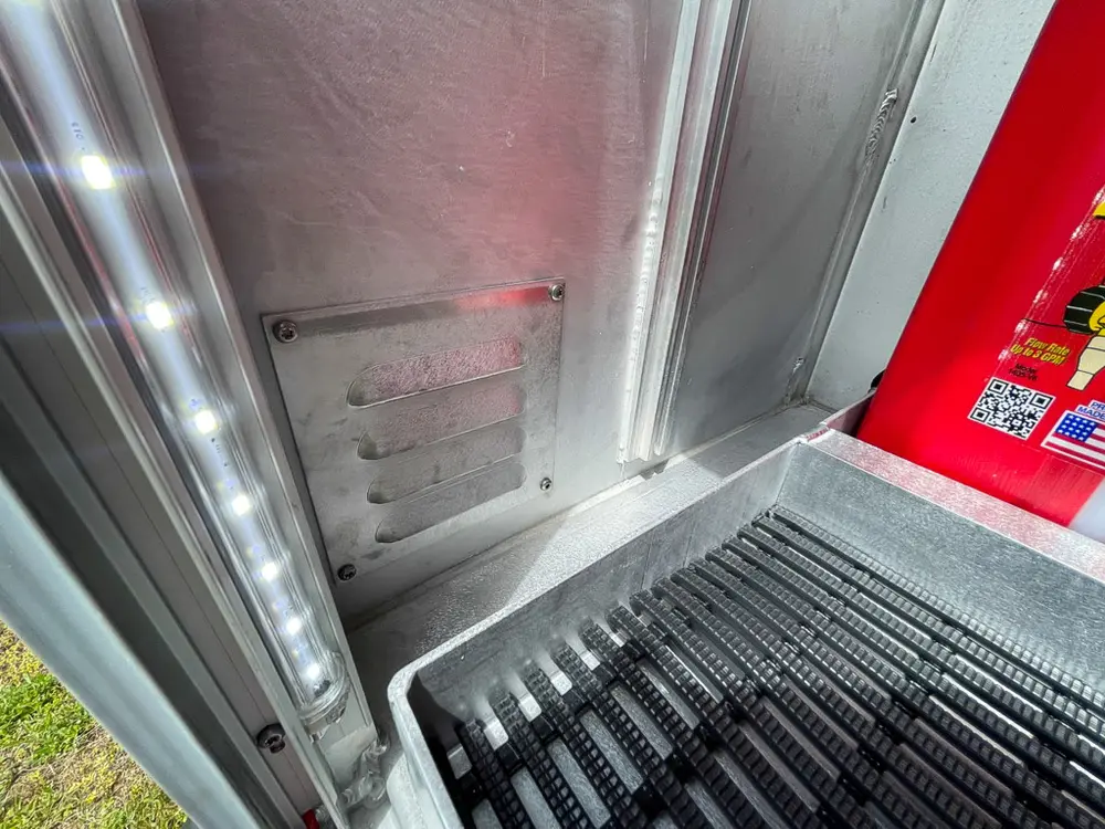 Exterior view of small fire truck showing cab, body compartments, and wheel/tire area.