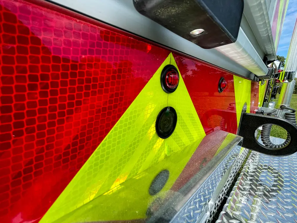 Exterior view of small fire truck showing cab, body compartments, and wheel/tire area.