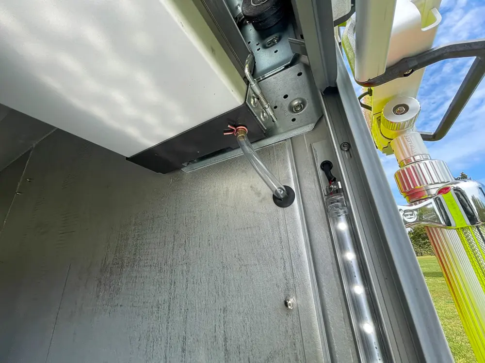 Exterior view of small fire truck showing cab, body compartments, and wheel/tire area.