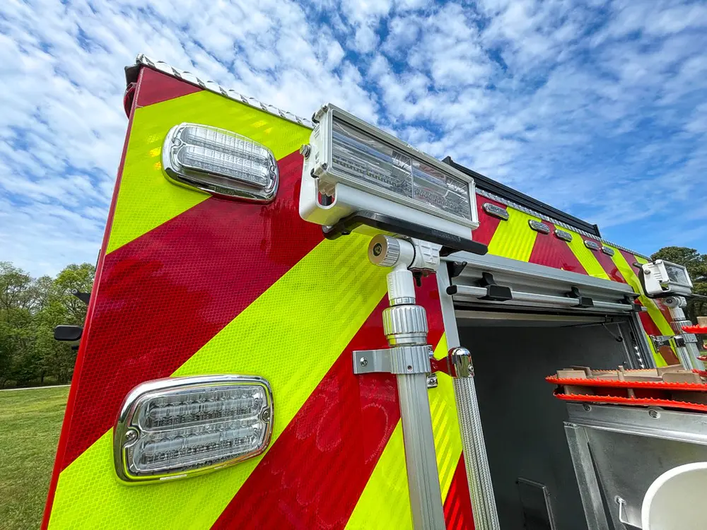 Exterior view of small fire truck showing cab, body compartments, and wheel/tire area.