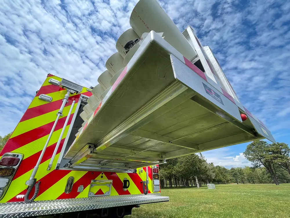Exterior view of small fire truck showing cab, body compartments, and wheel/tire area.