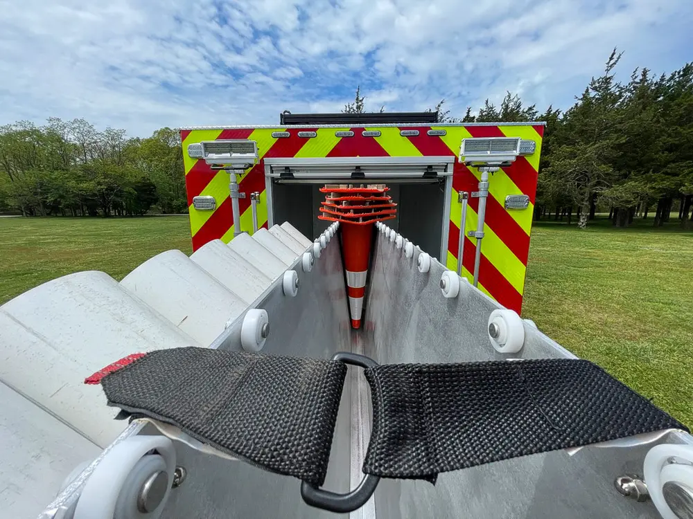 Exterior view of small fire truck showing cab, body compartments, and wheel/tire area.