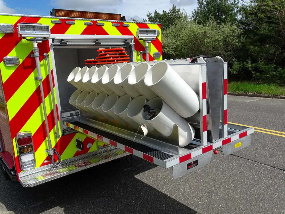 Exterior view of small fire truck showing cab, body compartments, and wheel/tire area.