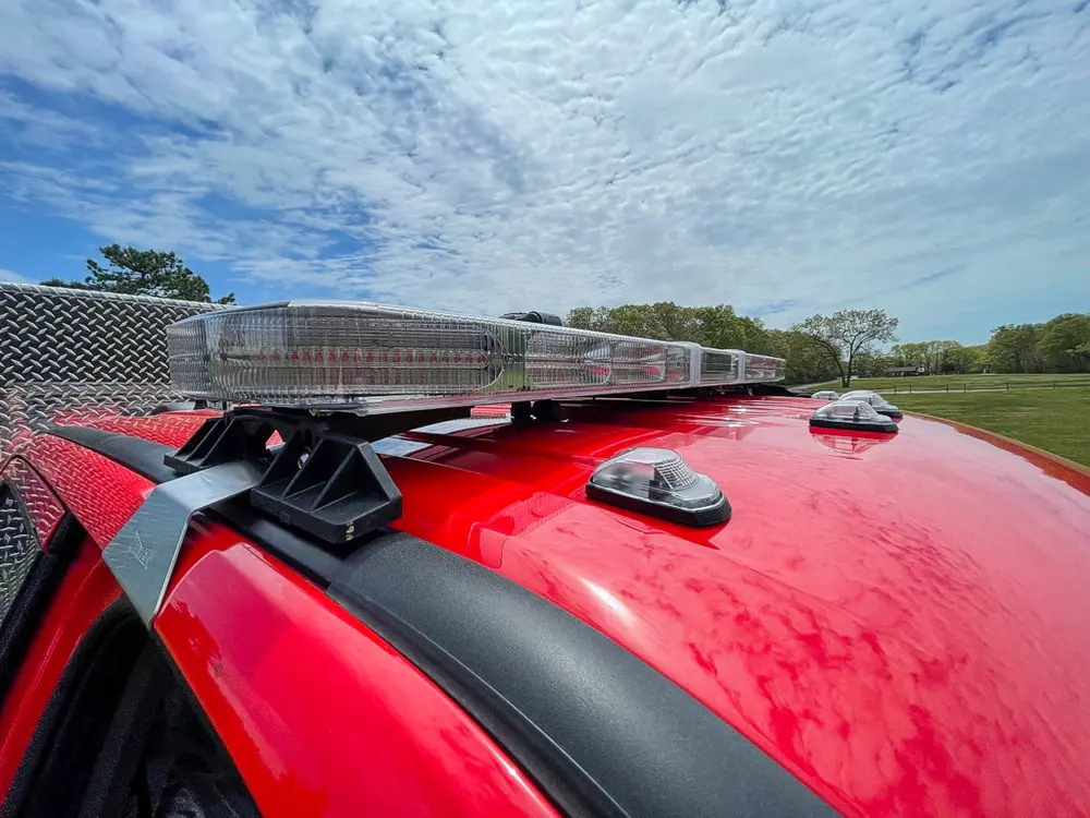 Exterior view of small fire truck showing cab, body compartments, and wheel/tire area.