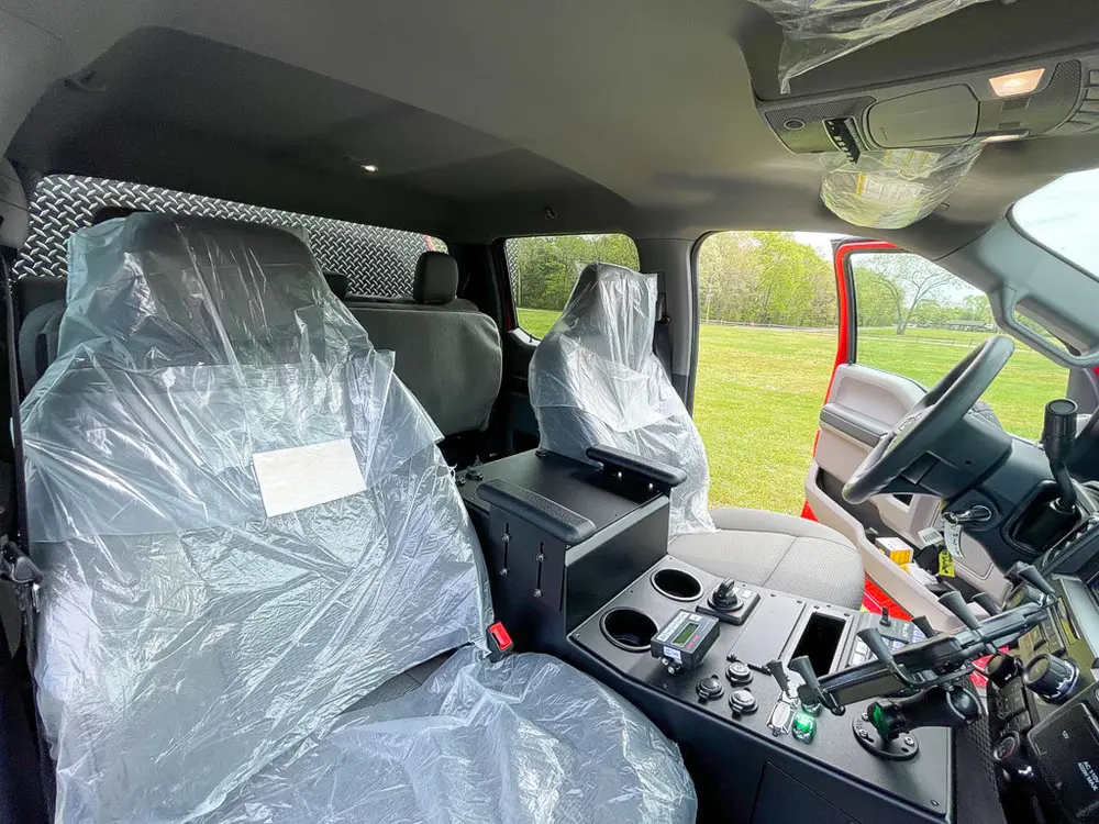 Exterior view of small fire truck showing cab, body compartments, and wheel/tire area.
