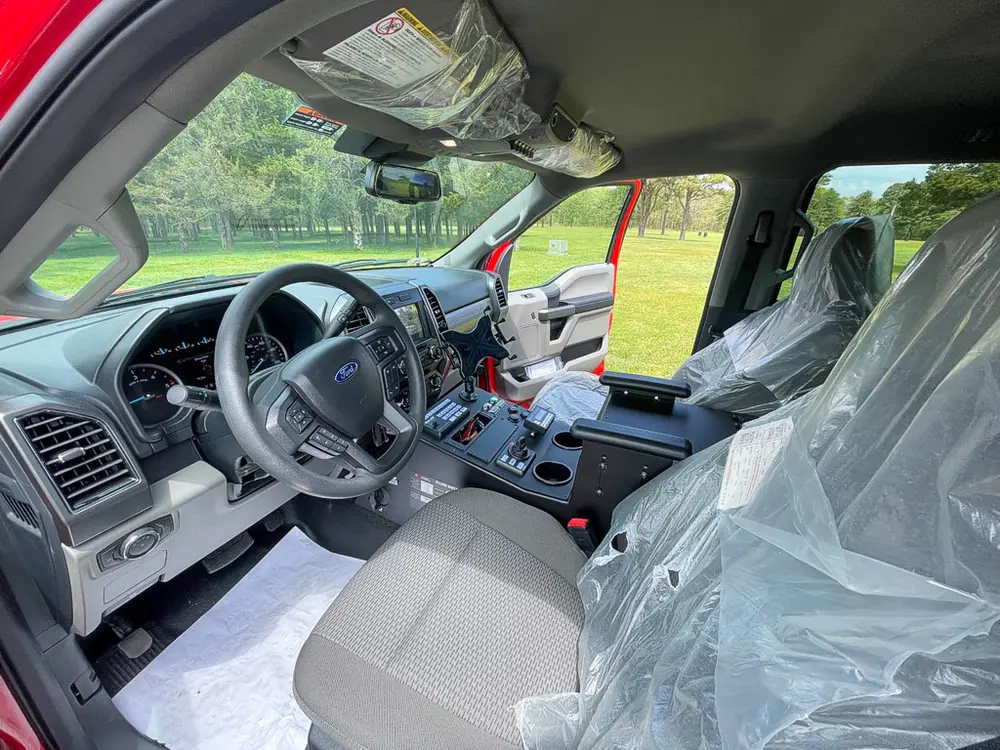 Exterior view of small fire truck showing cab, body compartments, and wheel/tire area.