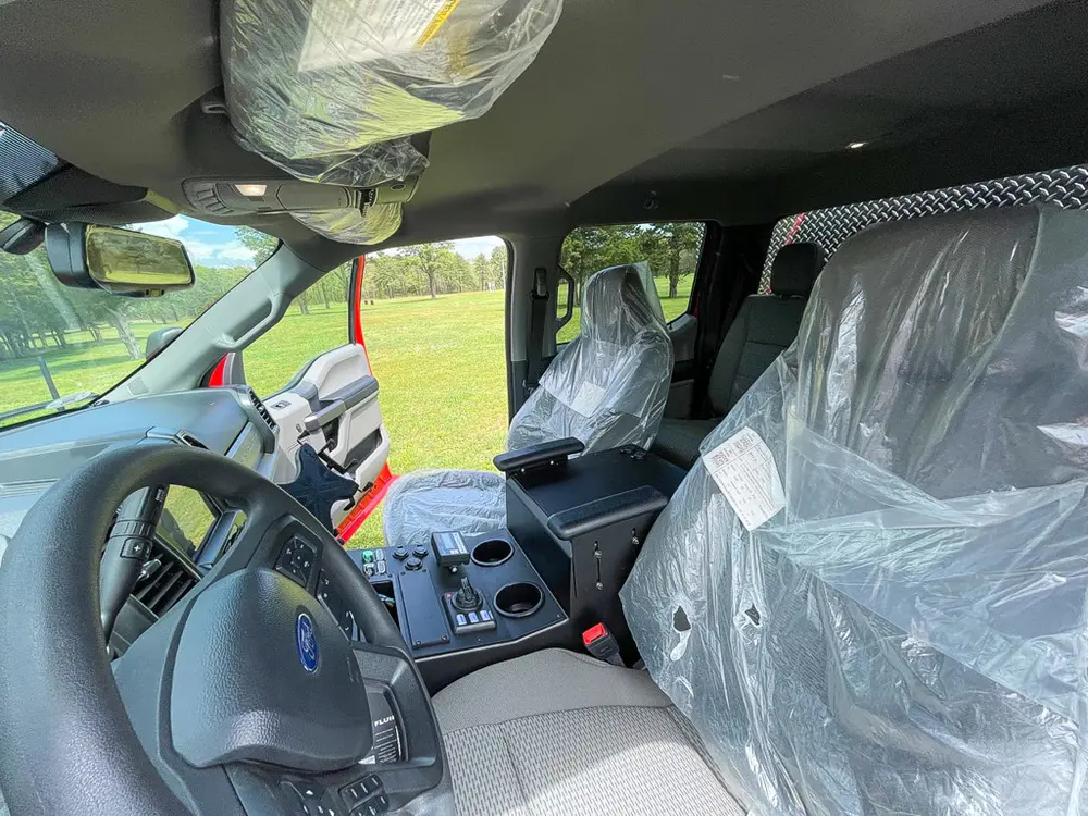 Exterior view of small fire truck showing cab, body compartments, and wheel/tire area.