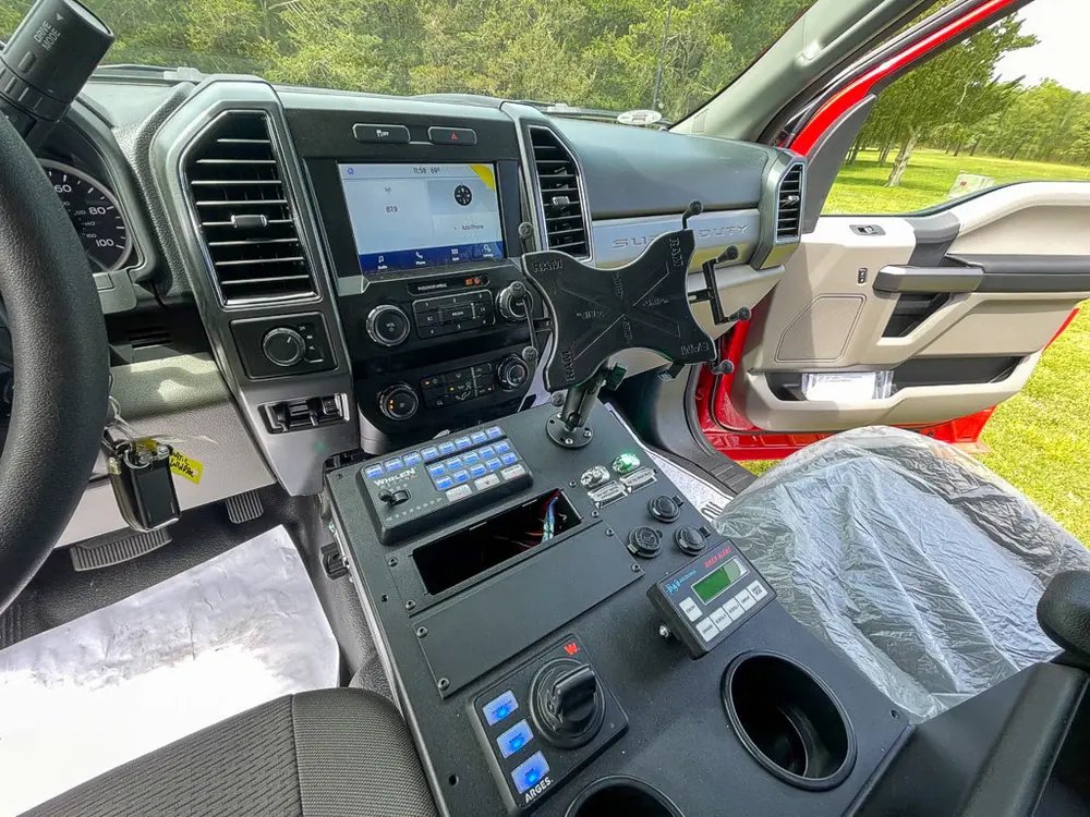 Exterior view of small fire truck showing cab, body compartments, and wheel/tire area.