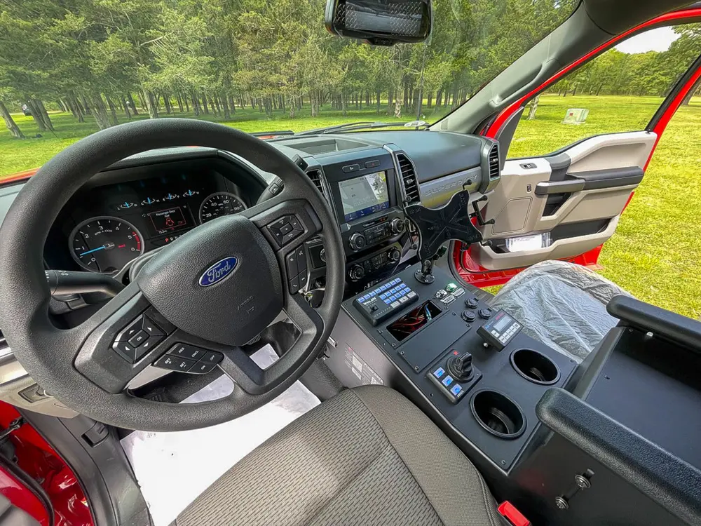 Exterior view of small fire truck showing cab, body compartments, and wheel/tire area.