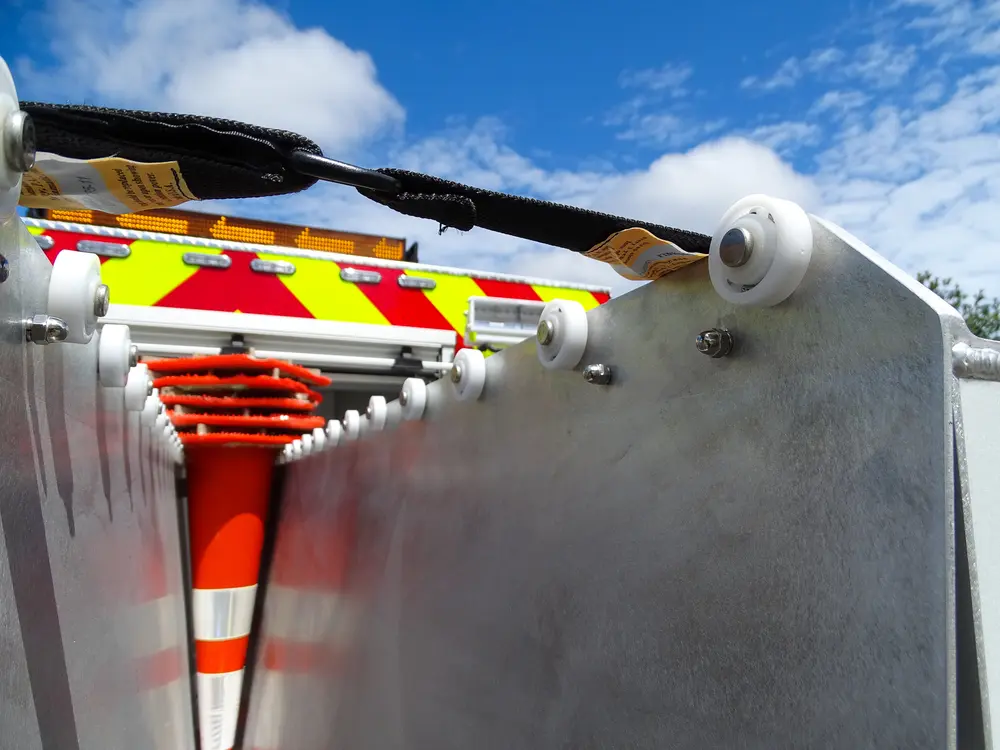 Exterior view of small fire truck showing cab, body compartments, and wheel/tire area.