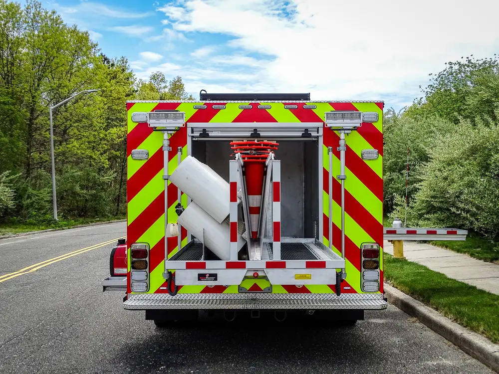 Exterior view of small fire truck showing cab, body compartments, and wheel/tire area.