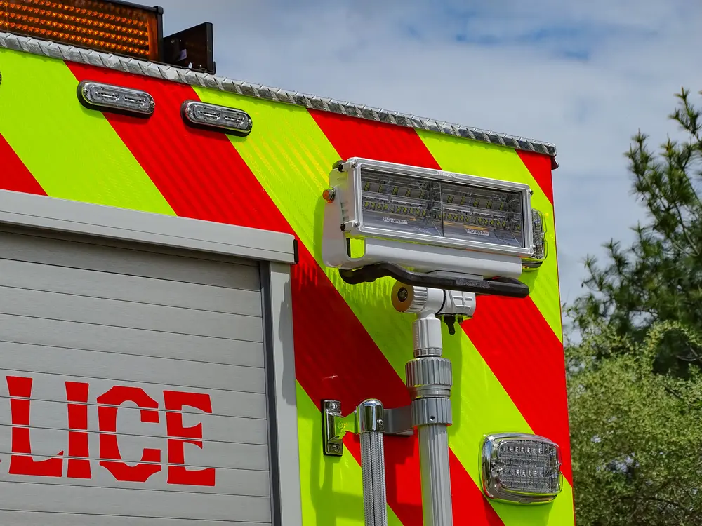 Exterior view of small fire truck showing cab, body compartments, and wheel/tire area.