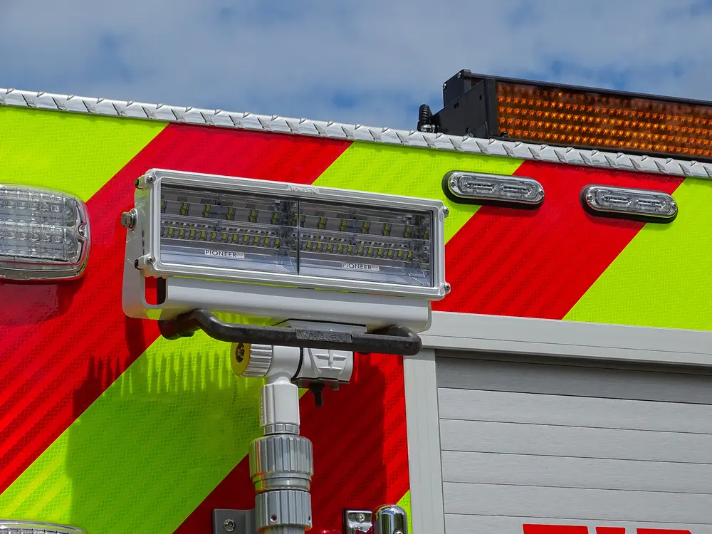 Exterior view of small fire truck showing cab, body compartments, and wheel/tire area.