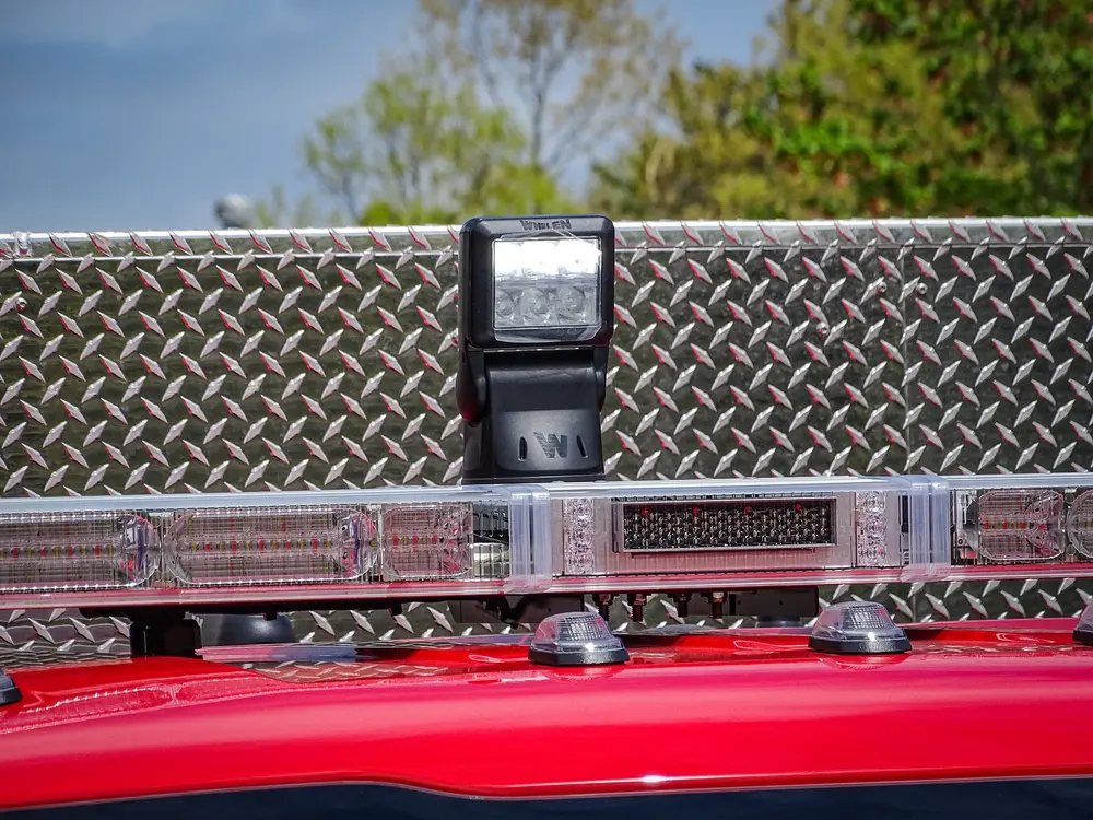 Exterior view of small fire truck showing cab, body compartments, and wheel/tire area.