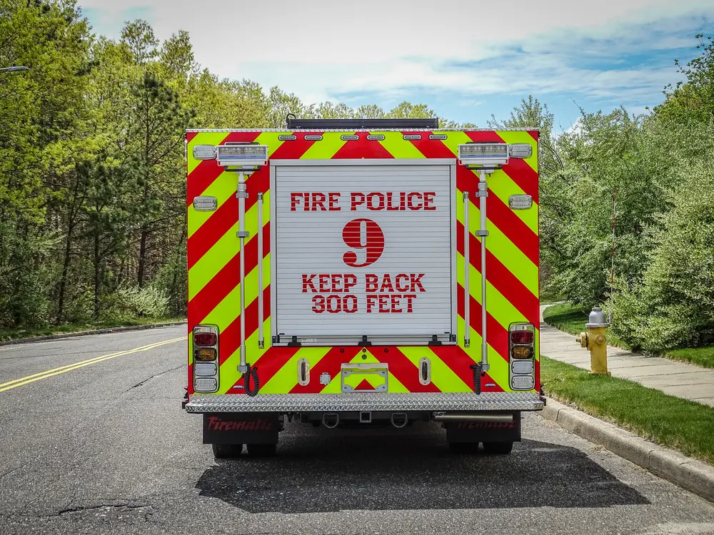 Exterior view of small fire truck showing cab, body compartments, and wheel/tire area.