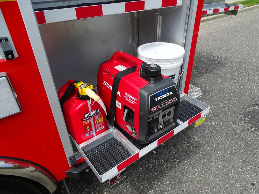Exterior view of small fire truck showing cab, body compartments, and wheel/tire area.