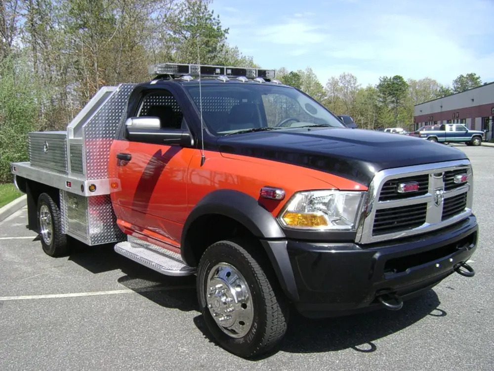 Exterior view of small fire truck showing cab, body compartments, and wheel/tire area.