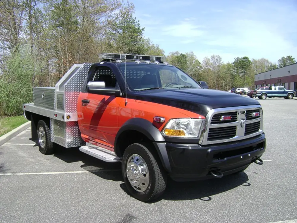 Exterior view of small fire truck showing cab, body compartments, and wheel/tire area.