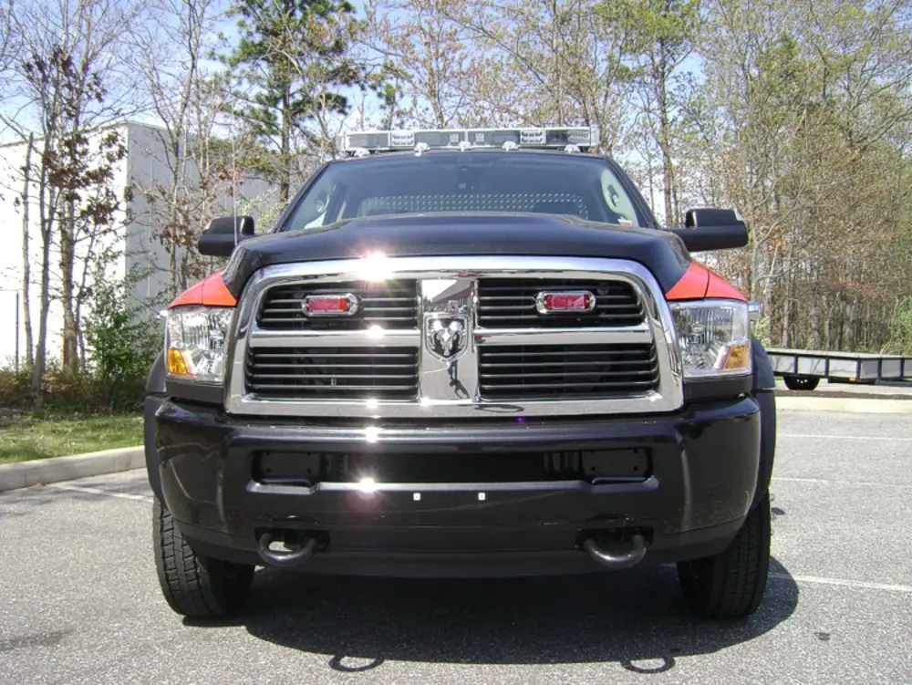 Exterior view of small fire truck showing cab, body compartments, and wheel/tire area.