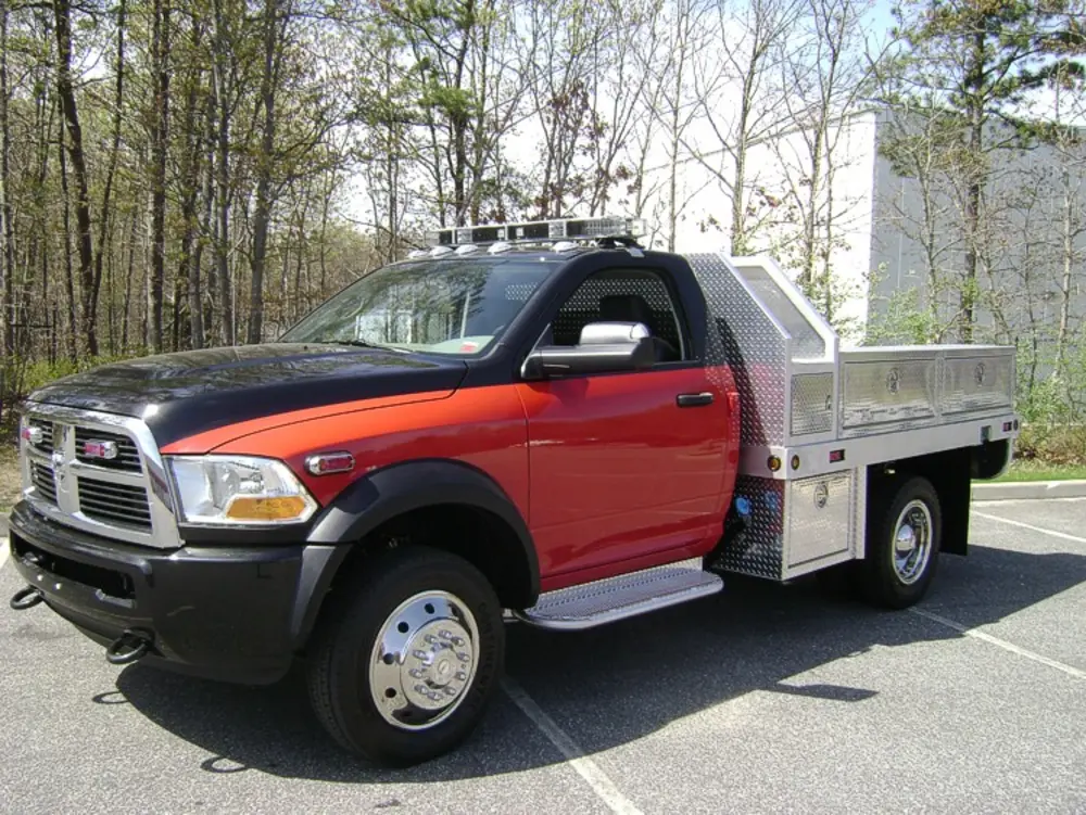 Exterior view of small fire truck showing cab, body compartments, and wheel/tire area.