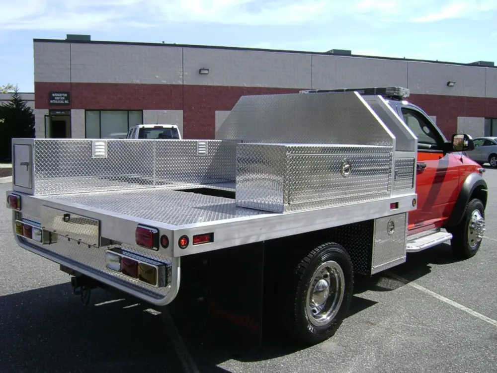 Exterior view of small fire truck showing cab, body compartments, and wheel/tire area.
