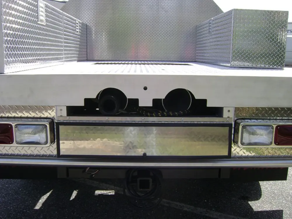 Exterior view of small fire truck showing cab, body compartments, and wheel/tire area.