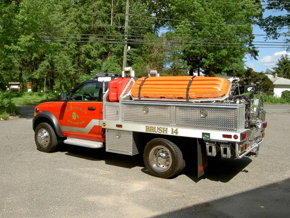 Exterior view of small fire truck showing cab, body compartments, and wheel/tire area.