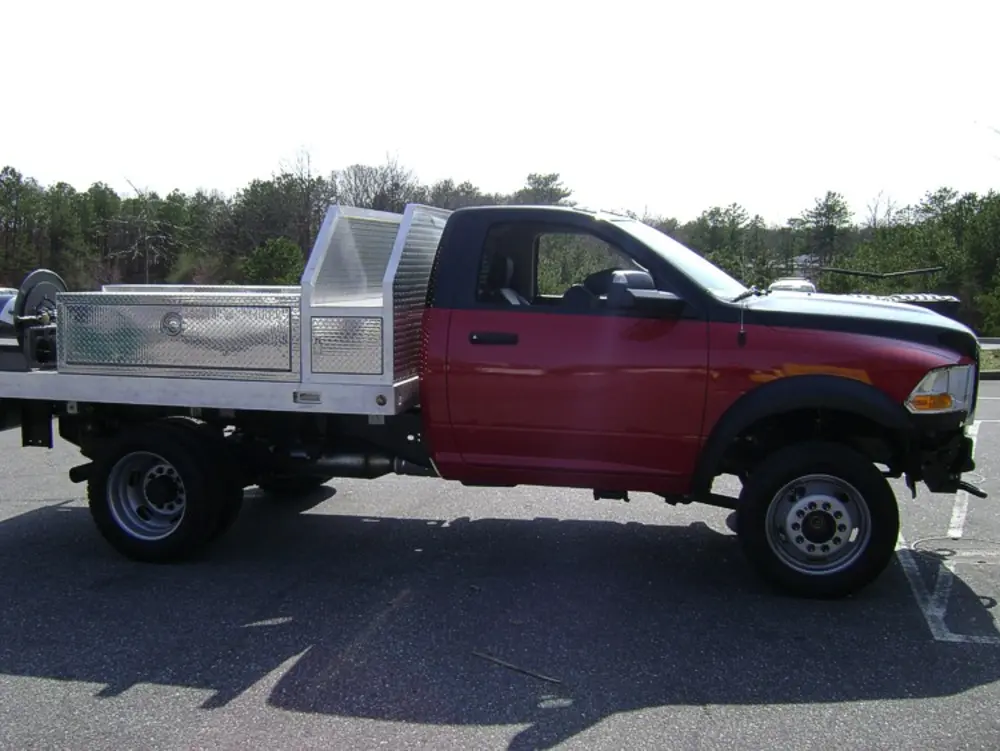 Exterior view of small fire truck showing cab, body compartments, and wheel/tire area.