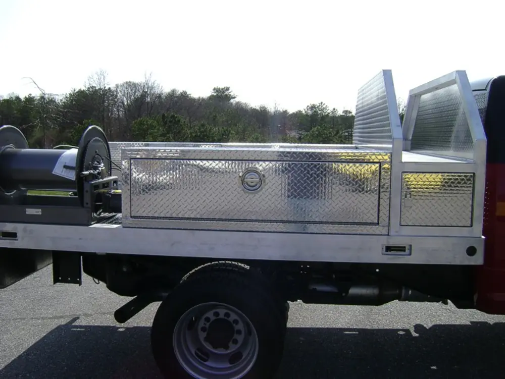 Exterior view of small fire truck showing cab, body compartments, and wheel/tire area.