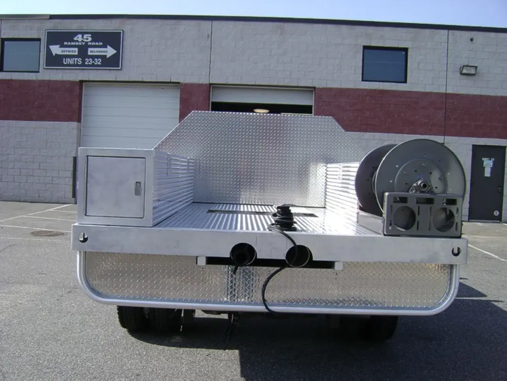 Exterior view of small fire truck showing cab, body compartments, and wheel/tire area.