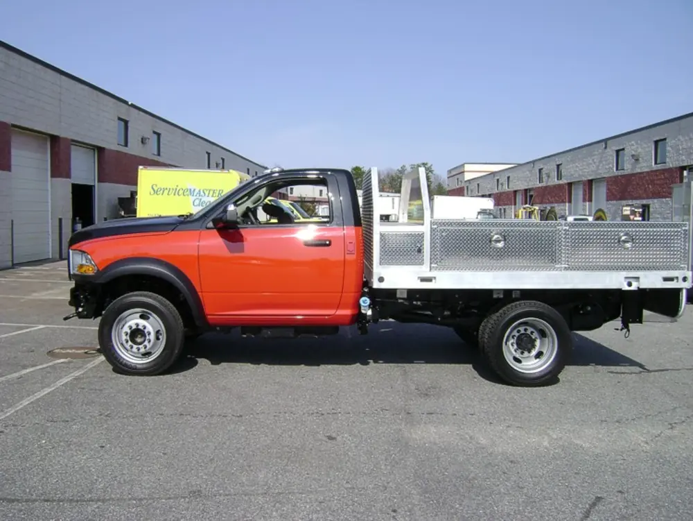 Exterior view of small fire truck showing cab, body compartments, and wheel/tire area.