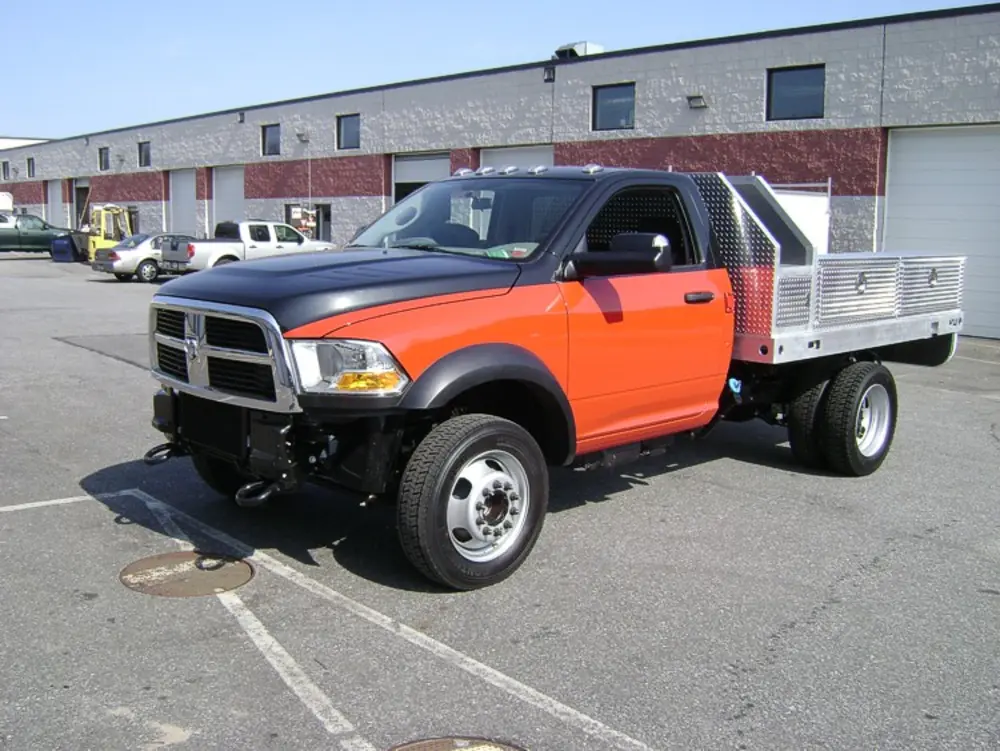 Exterior view of small fire truck showing cab, body compartments, and wheel/tire area.