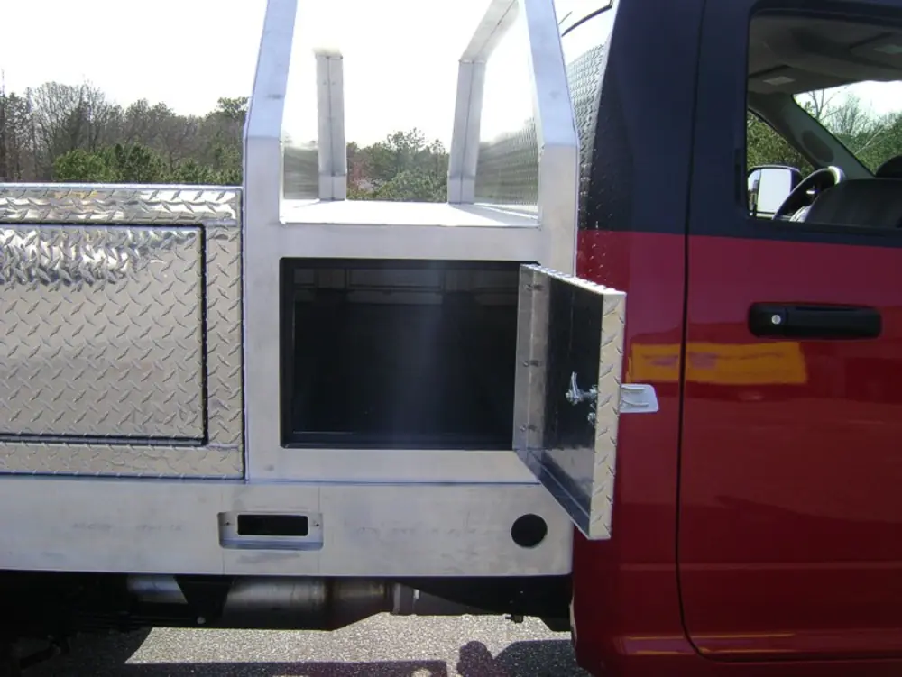 Exterior view of small fire truck showing cab, body compartments, and wheel/tire area.